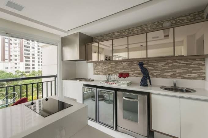 Cozinha de varanda com bancada branca e armários com vidro